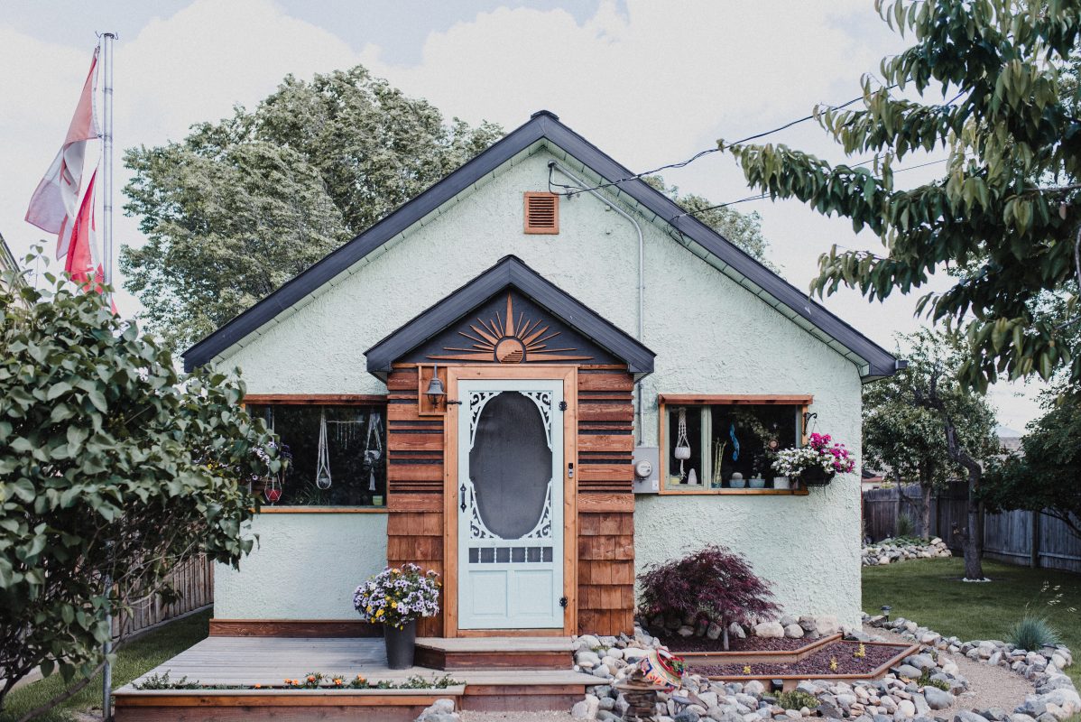 A cute, white character home in Kamloops, BC with wood details and a mature garden.