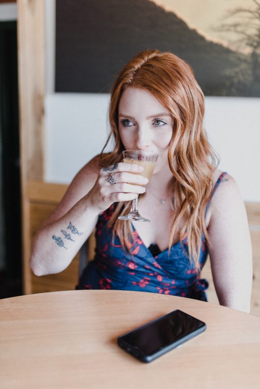 A beautiful woman with red hair living in Kamloops sips a beer at Bright Eye Brewing.