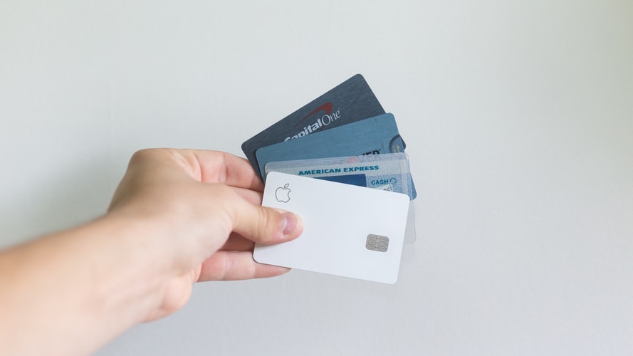 A hand holding several types of credit cards which can be used to increase your credit score.