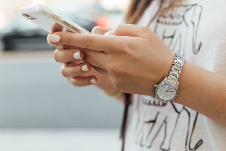 A woman wearing a watch and holding a cell phone.