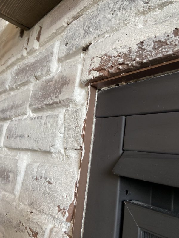 The corner of a fireplace where it meets a faux brick wall with german smear mortar whitewash over it.