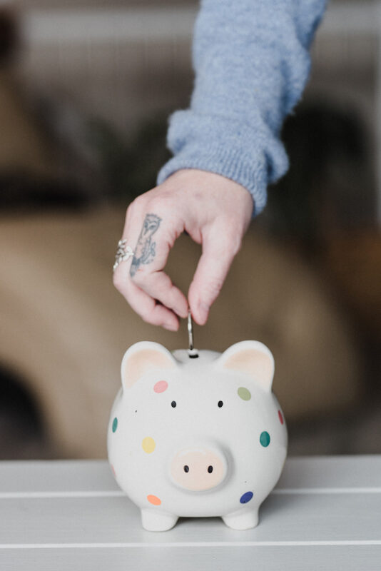 A Gen Z drops a coin into a piggy bank in order to save money.
