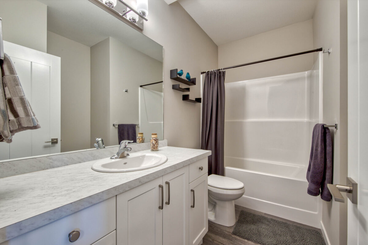 A clean and modern bathroom with light grey walls and crisp white cabinets in a Kamloops Airbnb.