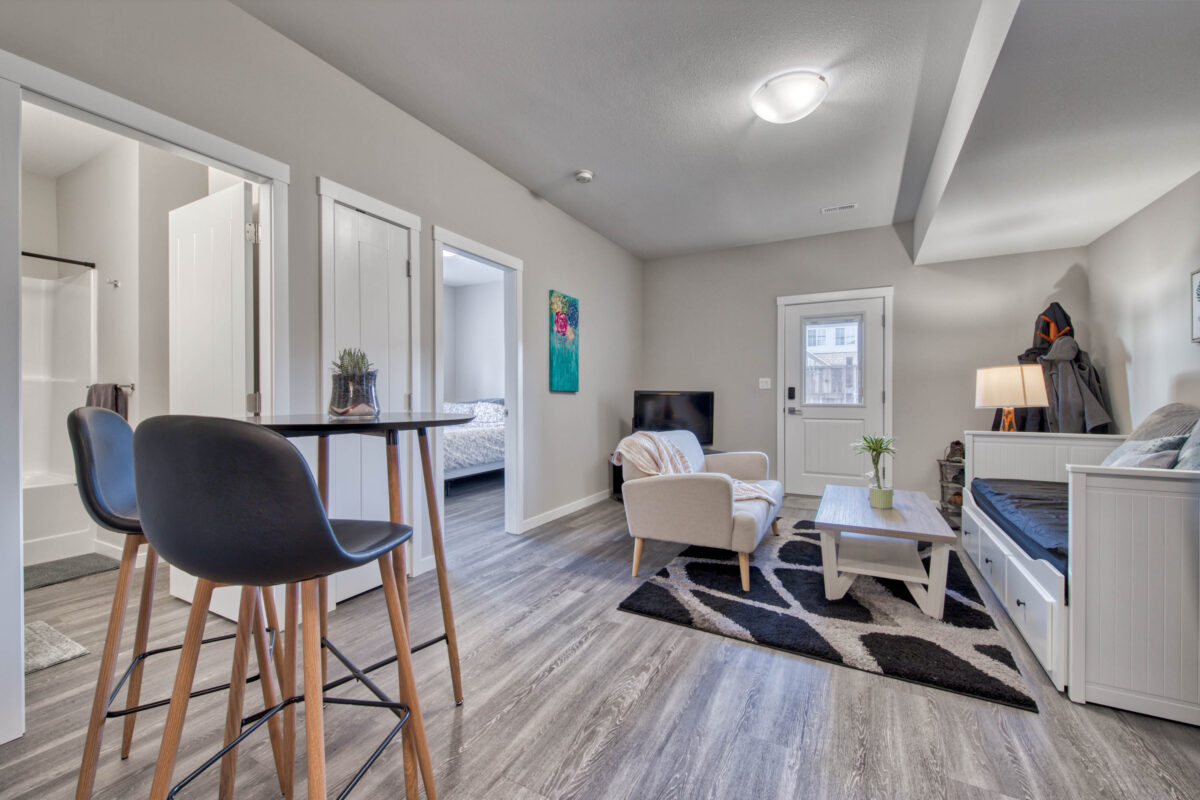 An open-concept living and dining space with light grey walls and modern furniture in an Airbnb in Kamloops.