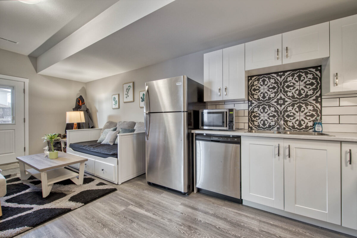 The interior of a well-staged Airbnb with an open-concept kitchen and living space, clean and modern paint colors, and light wood flooring.