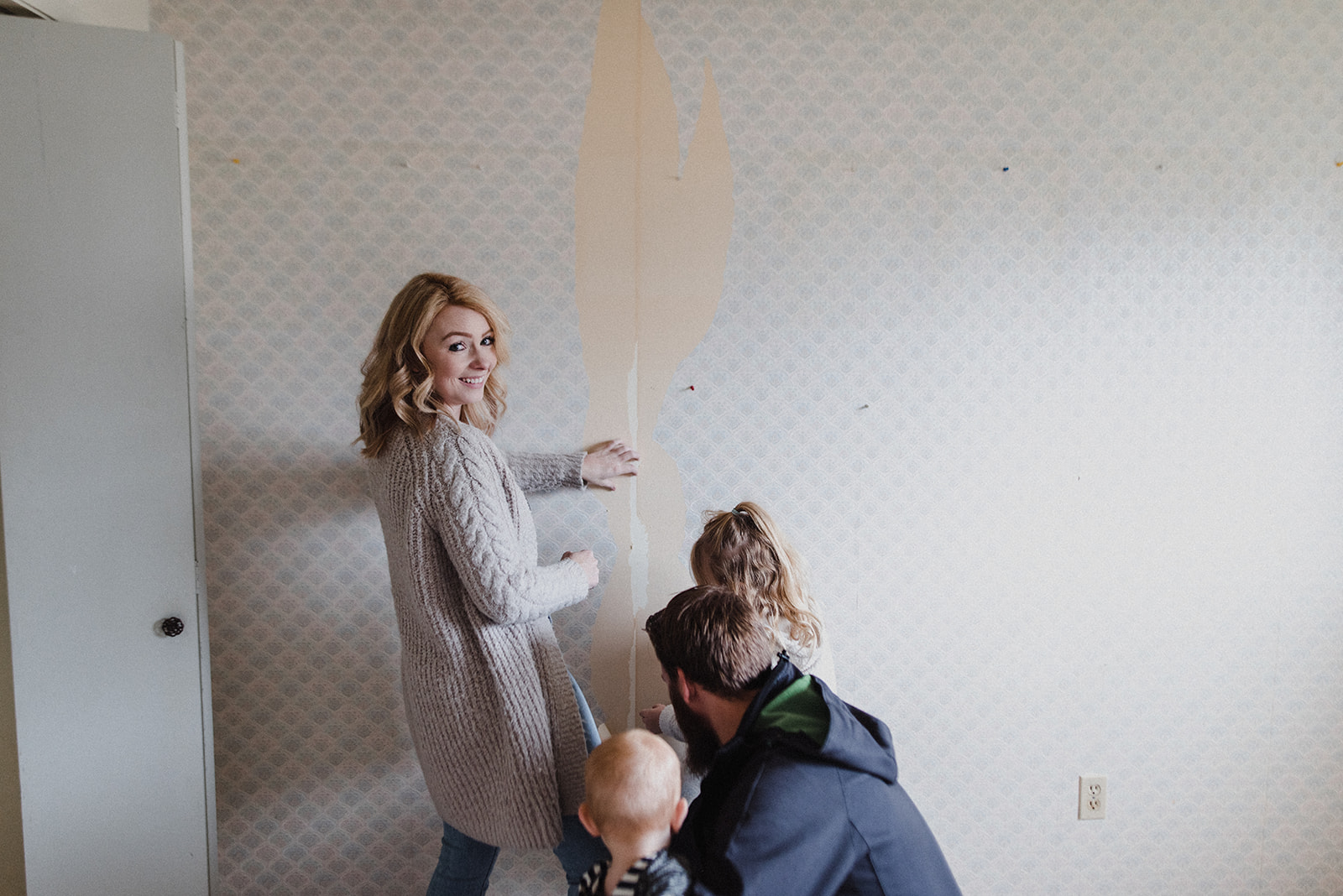 Kamloops Realtor Skyleigh McCallum smiles while pulling wallpaper off with her family in their renovation project home.