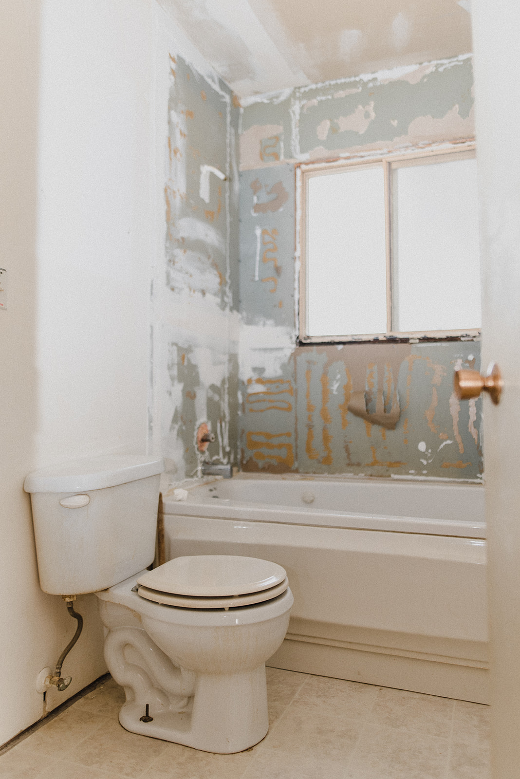 A bathroom in mid-renovation, with tiles missing from the shower. 