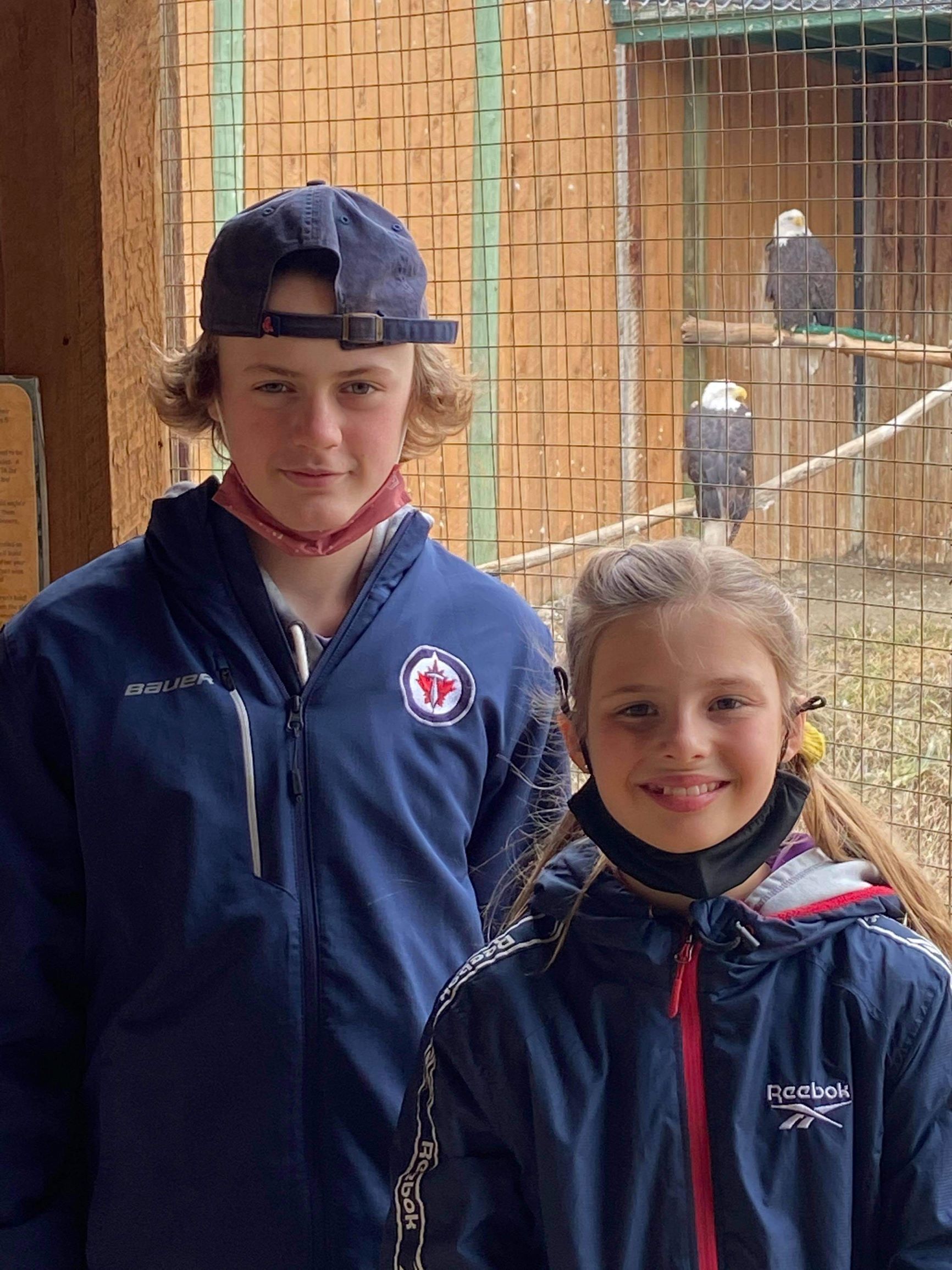 Two kids, a boy and a girl, stand in front of the bald eagle sanctuary at the BC Wildlife Park in Kamloops.