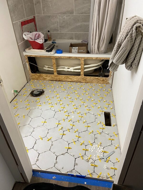 Bathroom floor tiling being placed in a home in Kamloops being renovated by Realtor Skyleigh McCallum.