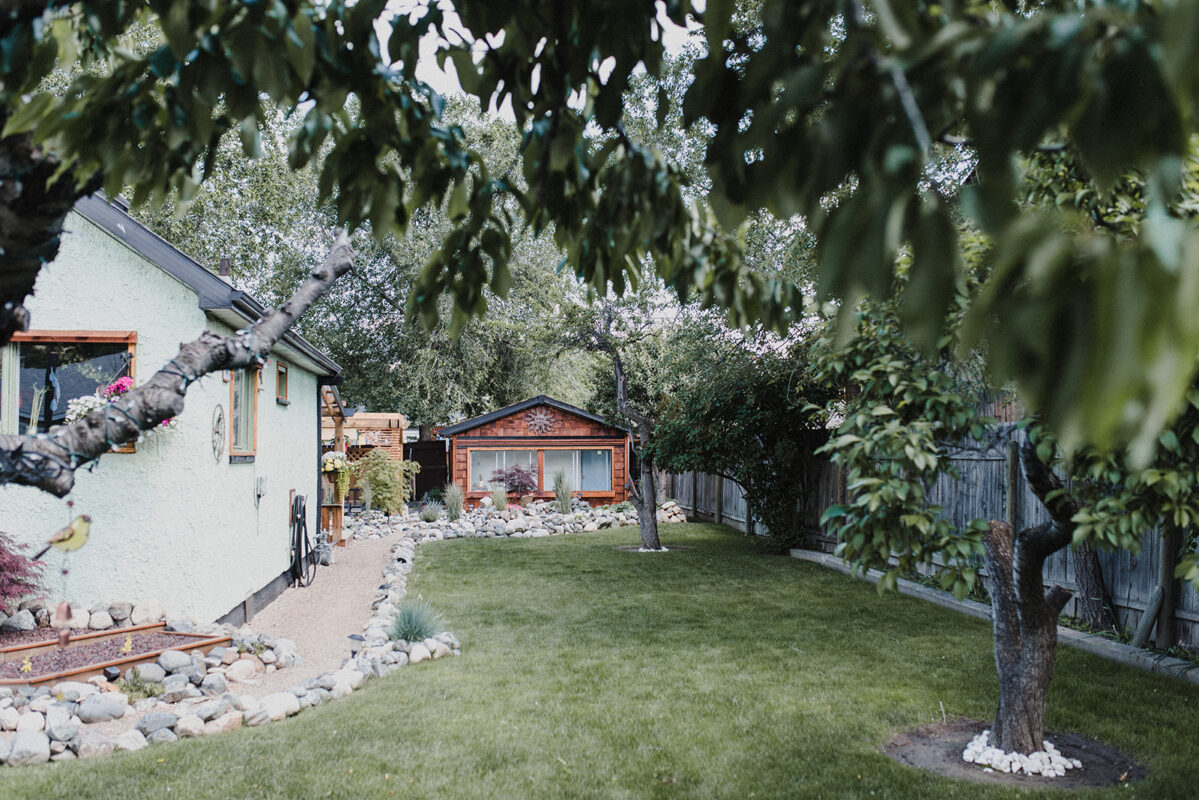 laneway house in back yard with grass and trees in front