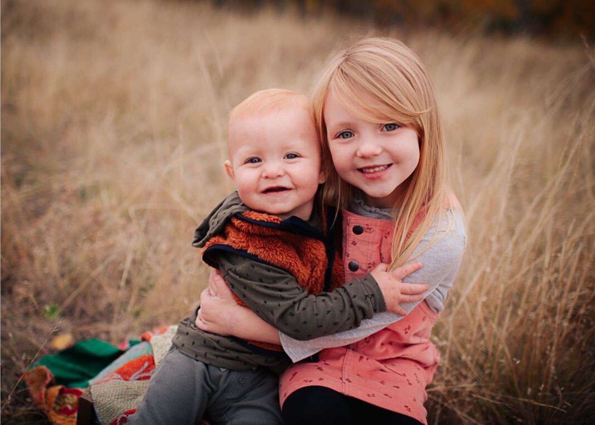 Skyleigh's children posing for a photo together smiling side by side in the fall grass